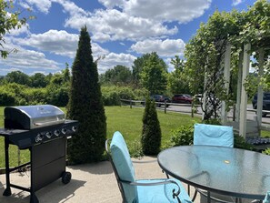 A patio with a grill, a table, and chairs.