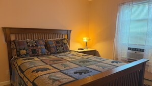 A bed with a quilt, a bedside lamp, and an air conditioning unit. - Grandview Private 2 room suite, 5 minutes to Dreams Park, close to town (Milford)