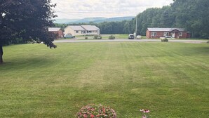 A well-maintained lawn with a flower bed and a paved walkway leading to a building. - Grandview Private 2 room suite, 5 minutes to Dreams Park, close to town (Milford)