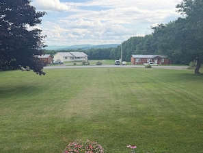 A grassy field with a house and a truck parked in the background.