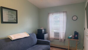 A room with a grey sofa, a framed sign on the wall, a window with blinds, a clock, and a small table with items on it. - Grandview Private 2 room suite, 5 minutes to Dreams Park, close to town (Milford)