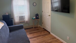 A room with a bed, a television mounted on the wall, a door, and a window with curtains. - Grandview Private 2 room suite, 5 minutes to Dreams Park, close to town (Milford)