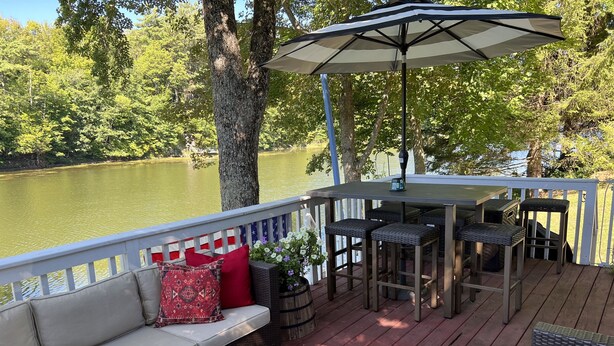 Een terras met een bank, stoelen en een tafel met een parasol.