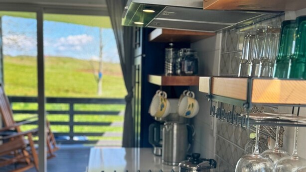 A modern kitchen with a gas stove, wooden cabinets, and a view of the outdoors. - Grousehall Total Renovation, contemporary design, short drive to Cooperstown (Schuyler Lake)
