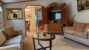 Un salon comprenant un canapé, une table basse, un meuble pour la télévision et un coin repas avec des chaises et une table.