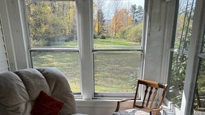 A room with a large window, a sofa, a chair, and a small table. - Hemlock - Quiet neighborhood, fire pit, large backyard, near All Star Village (Oneonta)