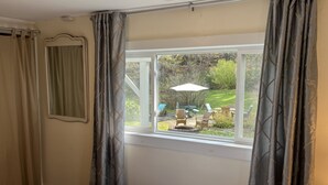 A bedroom with a large window, a bed, and a view of an outdoor patio area. - Hemlock - Quiet neighborhood, fire pit, large backyard, near All Star Village (Oneonta)
