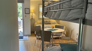Un dormitorio con literas, una mesita, sillas y una ventana.