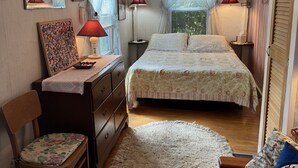 Un dormitorio con una cama, un escritorio, una silla, un ventilador de techo y dos lámparas de noche.