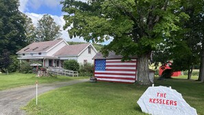 Una casa con un granero rojo, una bandera y un cartel que dice "The Kesslers".