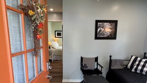 A room with a bed, a bench, a ceiling fan, and a door with a decorative wreath.