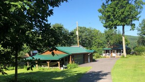A building with a green roof, a covered porch, and a driveway leading to a gated entrance.