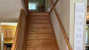 A wooden staircase with a handrail and a sign that reads "FOLLOW YOUR DREAMS THEY KNOW THE WAY."