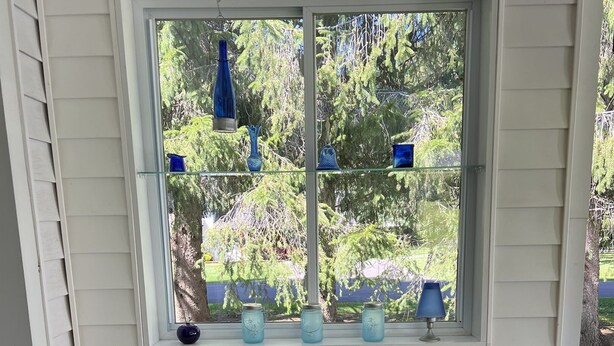 Een veranda met twee witte stoelen en een kleine tafel, versierd met blauwe kussens en een bloempot.