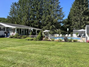 Una casa con piscina, rodeada de setos y follaje.