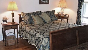 A bedroom with a bed, two bedside tables, two lamps, and two framed pictures on the wall.
