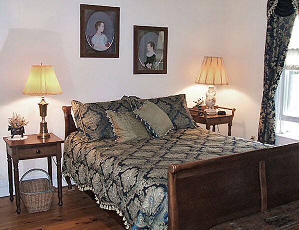 Un dormitorio con cama, dos mesitas de noche, dos lámparas y dos cuadros en la pared.