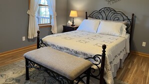 A bedroom with a bed, a nightstand, a lamp, a bench, a window with curtains, and a wall decoration. - Pagey's Place - Peaceful country setting, fire pit, Foosball, amazing views (Cooperstown)