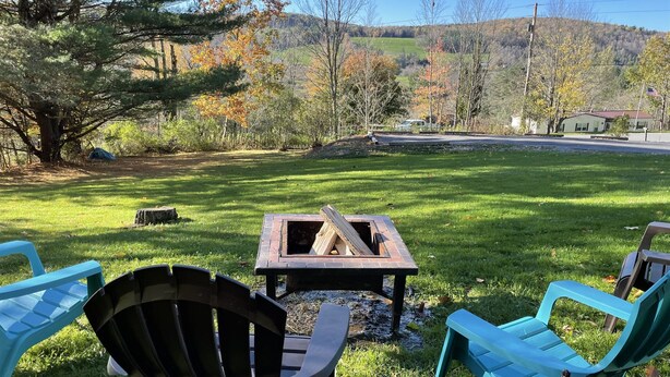 A grassy outdoor area with a fire pit, two Adirondack chairs, and a tent. - Pagey's Place - Peaceful country setting, fire pit, Foosball, amazing views (Cooperstown)