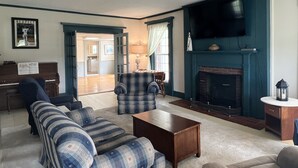Ein Wohnzimmer mit Kamin, Fernseher, Klavier und einer Couch.
