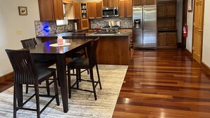 A modern kitchen with wooden cabinets, a stainless steel refrigerator, and a built-in microwave. - Phoenix Hill - Spacious, 7bdrm home, pool, game room and long distance views (West Oneonta)