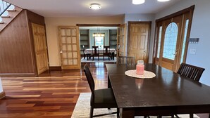 A spacious dining area with a long wooden table, black chairs, and a patterned placemat. - Phoenix Hill - Spacious, 7bdrm home, pool, game room and long distance views (West Oneonta)