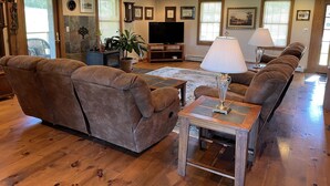 Un salon avec un canapé en cuir marron, une table basse en bois, un téléviseur et une lampe.