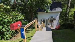 A house with a wooden deck leading to a front door, surrounded by greenery. - Pioneer Cottage Pristine 1 bedroom home, 5 minutes to All Star, private patio (Oneonta)