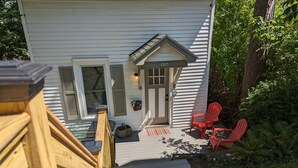 A house with a porch, a wooden deck, and two red Adirondack chairs. - Pioneer Cottage Pristine 1 bedroom home, 5 minutes to All Star, private patio (Oneonta)