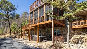 A two-story building with a stone facade, wooden balconies, and a hot tub in the outdoor area. - Updated Flooring, New Hot Tub, Resort Amenities! (Mc Gaheysville)