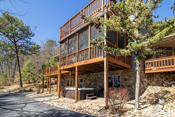 A two-story building with a stone facade, wooden balconies, and a hot tub in the outdoor area.