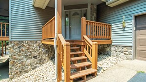 A house with a stone foundation, wooden steps, and a garage door. - Updated Flooring, New Hot Tub, Resort Amenities! (Mc Gaheysville)