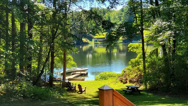 Udsigt over en sø med en anløbsbro, picnicbord og stole.