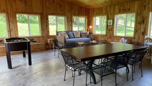 A cozy room with a wooden interior, a foosball table, a sofa, and a dining table with chairs.