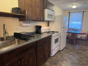 A kitchen with a stainless steel sink, a microwave, a stove, and wooden cabinets. - Sunnyside Apartment 1#, 1 of 3 - Great location, pool, 1/2 mile to Dreams Park (Cooperstown)