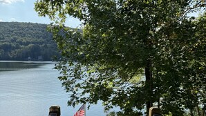 A wooden staircase leading to a dock with an American flag, surrounded by trees and a lake. - Sunset Waters -Goodyear Lake - hot tub, swimming ,fishing. paddle sports (Maryland)