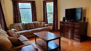 Una sala de estar con un sofá, una mesa de centro de madera, un televisor y un mueble.