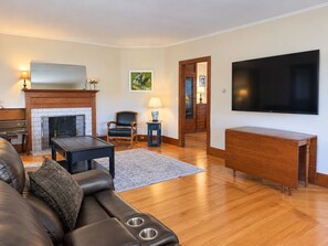 Una sala de estar con chimenea, un sofá, un televisor y una mesa de centro de madera.