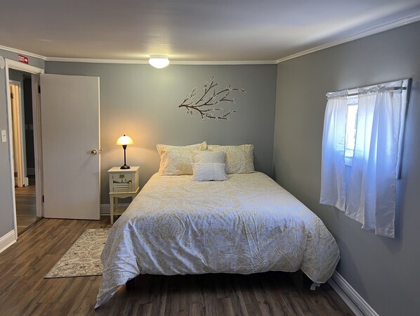 Un dormitorio con cama, mesita de noche, lámpara y una decoración de rama en la pared.