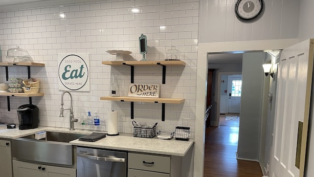 A modern kitchen with a dishwasher, a coffee maker, and a sign that says "Good Food Eat Served Here".