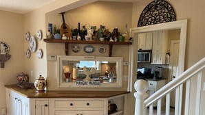 Una cocina con isla central, armarios blancos y varios objetos decorativos en las paredes.