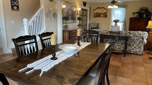 Un comedor con una mesa de madera, sillas y un camino de mesa decorativo.