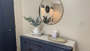 A bathroom vanity with a white vase of green foliage, a tissue box, and a round mirror. - Wake Robin Cottage - Recent renovation 4 bdrm/ 4 bath home close to tournaments (Oneonta)