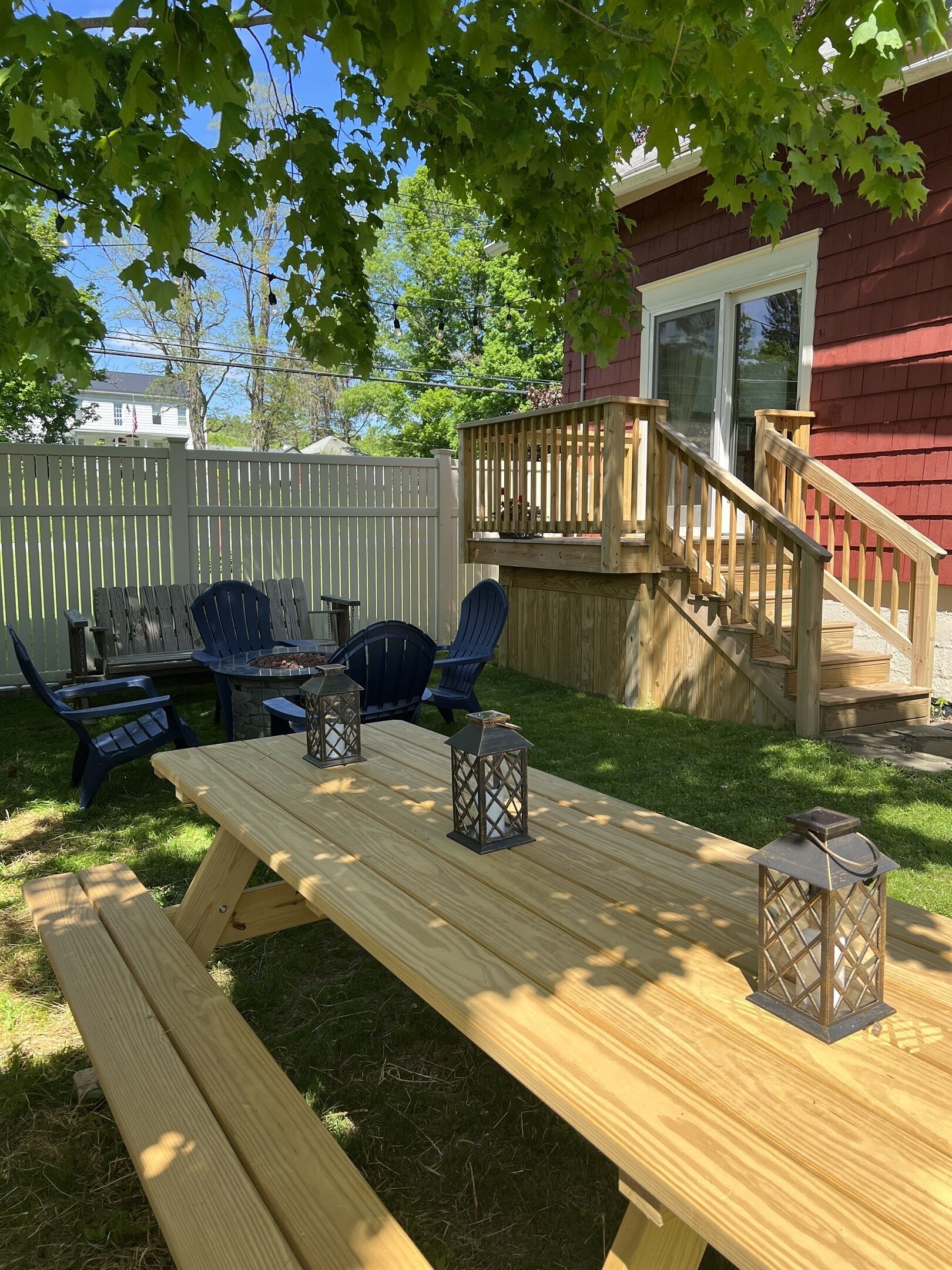 Un patio trasero con una terraza de madera, una mesa de picnic y mobiliario exterior.