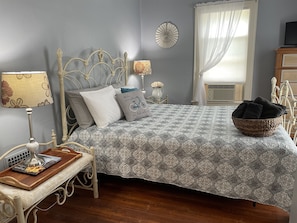 A bedroom with a bed, bedside tables, a lamp, a decorative wall piece, and a window with curtains. - Wake Robin Cottage - Recent renovation 4 bdrm/ 4 bath home close to tournaments (Oneonta)