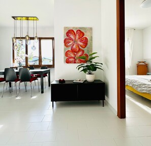Une chambre moderne comprenant un lit, une table de chevet, une grande fenêtre et un coin repas avec des chaises et une table.