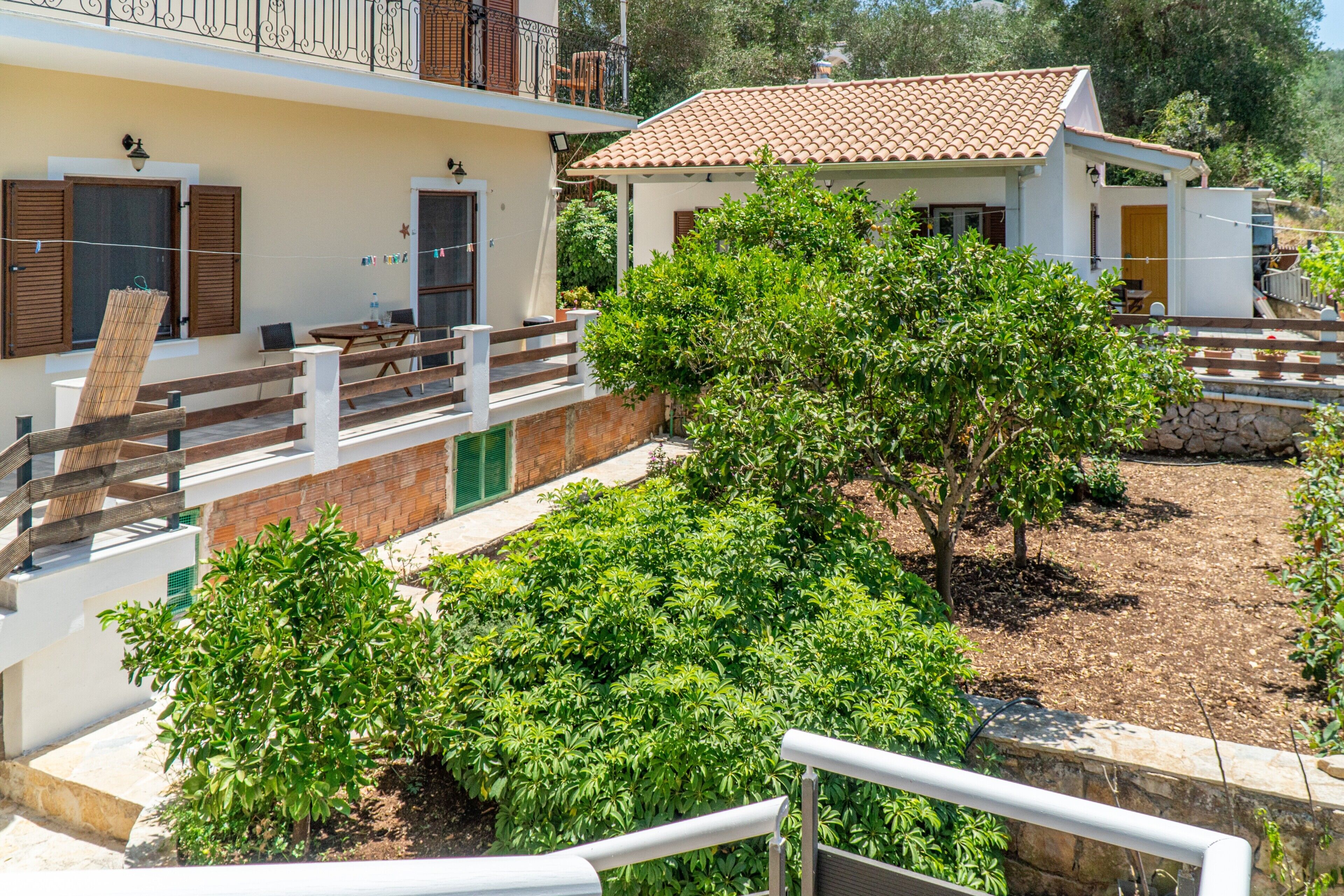 Un immeuble résidentiel doté d’un balcon, d’un petit jardin et d’une clôture en bois.