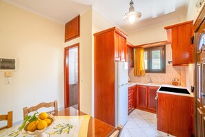 A kitchen with wooden cabinets, a refrigerator, and a dining table with chairs.