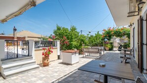 Une terrasse avec des meubles d’extérieur, un mur blanc et une vue sur la rue.