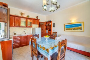 Una cocina con armarios de madera, una mesa de comedor con sillas, un refrigerador y un sofá.